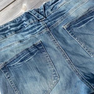 Blå bootcut jeans med stora fickor - Snygga blå jeans med bootcut passform och stora framfickor. Jeansen har klassisk femficksdesign, ljus tvätt och markerade sömmar. Perfekta för dig som gillar en avslappnad men trendig look.