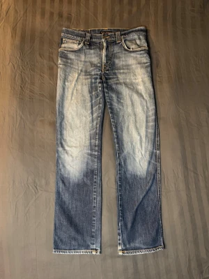Nudie slim jim bootcut  - Tja säljer ett par nudie jeans med riktigt snygg wash. Modellen heter slim jim och den sitter slim samt lite bootcut. Storleken på lappen är 34/32 men de sitter mer likt W32 L32.