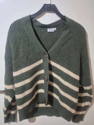 Grön och beige randig kofta VRS XL - Säljer en oversized stickad kofta från VRS Kollektion i storlek XL. Koftan är mörkgrön med breda beige ränder, har tre stora knappar framtill och ribbade muddar vid ärmslut och nederkant. Perfekt för lager-på-lager och chill stil.💚🛍