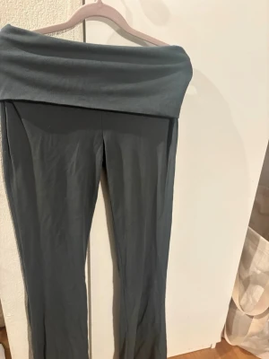 Mörkgröna nervikta leggings med bred linning - Säljer ett par mörkgröna leggings med bred, vikt linning. Byxorna har en rak passform och är gjorda i mjukt bomullsmaterial som är skönt mot huden. Perfekta för chill dagar eller när du vill vara extra bekväm.