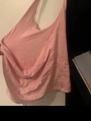 Rosa halterneck topp från Gina Tricot - Säljer en ljusrosa halterneck topp från Gina Tricot i storlek L. Toppen har en snygg draperad framsida och är ärmlös med smala axelband. Tillverkad av 97% ekologisk bomull, vilket gör den mjuk och skön mot huden. Perfekt för sommarens alla tillfällen!