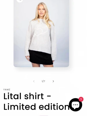 Ljusgrå stickad tröja med hjärtmotiv från YAMZ - Supermjuk och fluffig ljusgrå stickad tröja från YAMZ med ett stort vitt hjärtmotiv framtill. Tröjan har rund halsringning och långa ärmar, perfekt för att hålla sig varm och snygg under kyliga dagar. Lite skrynklig just nu men ska stryka den. Slut i lager nypris runt 500