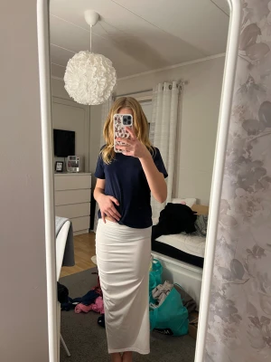 Vit långklänning från SHEIN - Snygg vit långklänning från SHEIN i storlek S. Klänningen är axelbandslös med en draperad detalj på sidan och har en slits framtill. Materialet är mjukt och har en lätt glansig finish, perfekt för dig som vill sticka ut med en clean och elegant look.