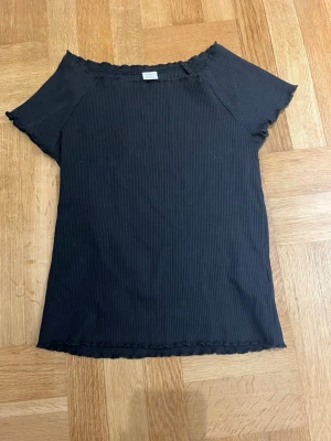 Svart off shoulder  - Säljer en svart ribbad topp från Lindex med korta ärmar och offshoulder-design. Passar xs. Aldrig använd❤️