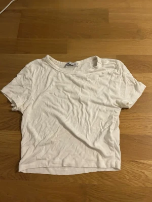 Vit t-shirt  - En basic vit t-shirt från Zara i mjuk bomull. Modellen är kortärmad med rund hals och har en enkel, clean look utan mönster eller detaljer. Perfekt att matcha med jeans eller shorts för en chill stil. Strl är i M men passar andra storlekar också, pga att den är stretchig 