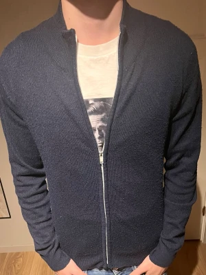 Mörkblå stickad kofta från ryvls/ kids brandstore  - Snygg mörkblå stickad kofta från Ryvls med dragkedja framtill och ribbade muddar vid ärmslut och nederkant. Koftan har en enkel, stilren design och passar perfekt till jeans eller chinos. Långärmad och med normal passform. Nypris: 599kr mitt pris 449 andvänd fåtal gånger!!