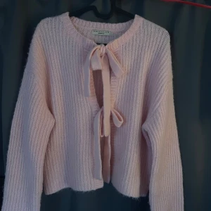 Ljusrosa stickad kofta från Gina Tricot - Superfin rosa stickad kofta från Gina Tricot med ribbad struktur och två söta knytband framtill. Tröjan är i storlek XS och är jätte fin och perfekt till hösten. Helt slutsåld, säljs för att den inte kommer till användning. Kontakta för egna bilder.