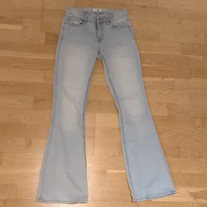 Ljusblå bootcut jeans från Lindex - Snygga ljusblå jeans från Lindex i modellen Freja. Jeansen har klassisk femficksdesign, dragkedja och knapp framtill samt bootcut-ben som ger en retro vibe. Perfekta för dig som gillar en avslappnad men trendig stil. (Pris kan diskuteras) 