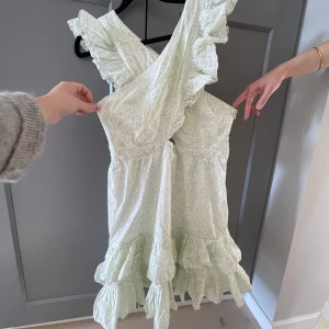 Ljusgrön volangklänning By Malina - Supersöt ljusgrön kortklänning från By Malina med blommigt mönster, omlott upptill och volanger på axlar och kjol. Tyvärr för stor för mig men underbart fin och aldrig använd! Pris kan diskuteras💕