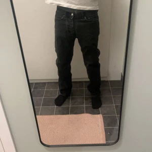 Svarta Weekday straight jeans - Säljer ett par Weekday 501 jeans med klassisk rak passform. Jeansen har fem fickor, knappgylf och är tillverkade i robust bomullsdenim. Perfekta för dig som gillar en tidlös och avslappnad stil. Har en liten färgfläck vid baksida