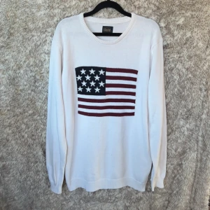 Vit stickad tröja med USA-flagga !Solid - Vit stickad tröja från !Solid med en stor amerikansk flagga på bröstet i marinblått, rött och vitt. Tröjan har rund halsringning och långa ärmar. 
