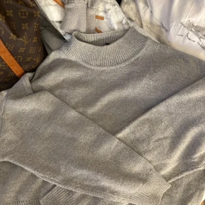 Grå stickad tröja från Divided - Mysig grå stickad tröja från Divided med högre ribbad halsringning och långa ärmar. Perfekt för lager-på-lager och enkel att matcha med jeans eller kjol. Klassisk och stilren modell som funkar året runt. Pris kan alltid diskuteras 🤍
