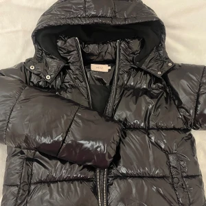 Svart pufferjacka från Nelly med huva - Snygg svart pufferjacka från Nelly. Perfekt för kalla dagar och ger en cool vibe till din outfit. Använd fåtal gånger! Nypris 800kr🫶