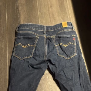 Mörkblå Replay jeans med kontrastsömmar - Snygga mörkblå jeans från Replay med klassiska kontrastsömmar och unika broderade bakfickor. Jeansen har låg midja och raka ben, tillverkade i mjukt denimtyg. Perfekta för dig som gillar en stilren och tidlös look.