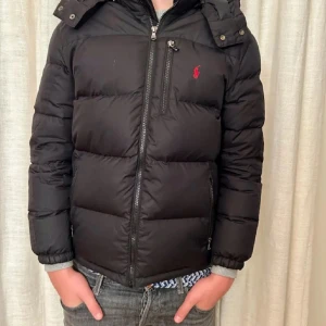 Svart pufferjacka Polo Ralph Lauren M - Svart pufferjacka från Polo Ralph Lauren.  jättebra skick .Jackan har huva med flera dragkedjefickor. Perfekt för kalla dagar och riktigt snygg till jeans. nypris 5500, pris kan diskuteras vid snabb affär