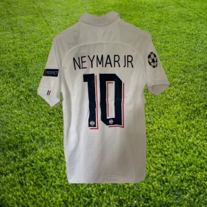 PSG Neymar Jr 19/20 - Säljer en vit PSG fotbollströja med Neymar Jr och nummer 10 på ryggen. Tröjan har även Champions League patches på ärmarna, röd och blå rand på framsidan samt klubbmärke. Fotbolmströjan är också helt oanvänd