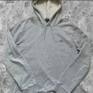 Sällsynt Grå hoodie från A.P.C. - Snygg ljusgrå hoodie från A.P.C. med minimalistiskt svart tryck på bröstet. Klassisk modell med huva och dragsko, ribbade muddar och mjukt bomullsmaterial. Perfekt för en clean och avslappnad stil. Storlek m men sitter som S. Pris kan diskuteras 