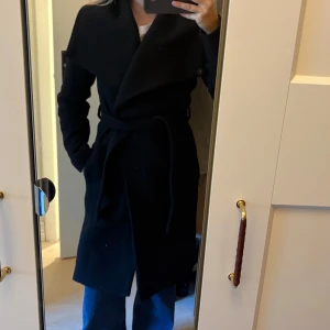 Kappa i ullmix från Mango - Svart kappa i ullmix från Mango. Går att ha kragen öppen eller knäppa den vid halsen, se bilder. Kappan är väl använd + har legat på vinden så luktar något ”instängd”💕