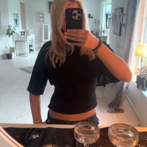 Svart croppad topp med öppen rygg - Säljer denna supersöta toppen som man knyter i ryggen, köpt från Nelly, nästan helt oanvänd