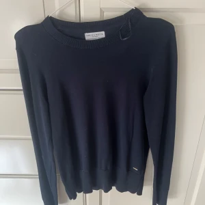 Mörkblå tröja från Holly & Whyte M - En stilren mörkblå tröja från Holly & Whyte by Lindex. Tröjan har rund halsringning, långa ärmar och en klassisk passform. Perfekt att matcha med jeans eller kjol för en enkel och snygg look.