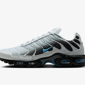 Nike Air Max Plus vit/svart/blå - Nike Air Max Plus sneakers i vitt, svart och blått med ikoniska vågformade detaljer och synlig Air Max-dämpning. Ovandel i mesh och syntet, svart sula med blå accenter och klassisk blå Swoosh. Skorna har snörning och en sportig vibe som sticker ut.