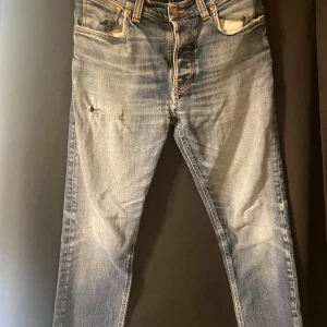 Nudie jeans Grim Tim - Säljer ett par klassiska blå jeans från Nudie Jeans med snygg slitning och kontrastsömmar. Modellen har raka ben och fem fickor, samt Nudie Jeans signaturbrodyr på bakfickorna. Perfekt för dig som gillar en avslappnad och tidlös look. (Modell Grim Tim) Pris kan diskuteras vid snabb och smidig affär