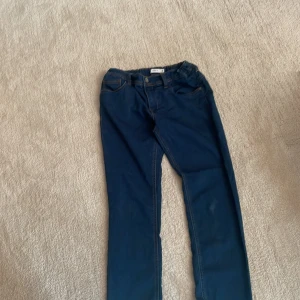 Mörkblå jeans från Name It - Snygga mörkblå jeans från Name It med klassisk femficksdesign och kontrastsömmar. Byxorna har resår i midjan för extra komfort och en rak passform. Perfekta för dig som gillar en enkel och stilren look.