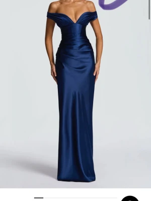 Marinblå långklänning i satin - Säljer en elegant marinblå långklänning i glansig satin med offshoulder och djup v-ringning. Klänningen har figurnära passform och vackra draperade detaljer upptill som ger en lyxig känsla. Perfekt för bal eller festliga tillfällen. Från babyboo. 