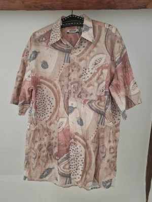Patterned short sleeve button up - Short sleeve button up in beige-red-blue pattern. Soft shirt fabric, and quite stable collar. No defects and all buttons are intact. Length: 80 cm