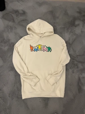 HM Hoodie - Krämvit hoodie med tryck fram och baksida. Storlek S.