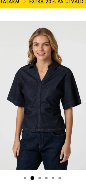 Mörkblå denimskjorta från Neo Noir - Snygg mörkblå skjorta i denim från Neo Noir med korta ärmar och markerade sömmar. Skjortan har en klassisk krage och v-ringad öppning framtill. Passformen är normal och materialet är bomull, vilket gör den både bekväm och stilren.