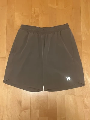 Grå träningsshorts från Lager 157 strl XL - Säljer ett par grå träningsshorts från Lager 157 i storlek XL. Märket på framsidan har reflex. Har två stycken sidofickor. Shortsen är i mycket bra skick. Färgen är ren grå i verkligheten.