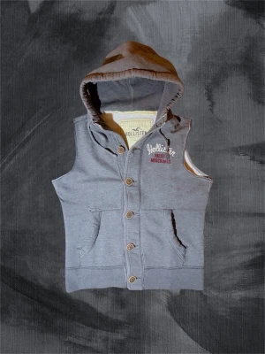 Grå hoodie-väst från Hollister - Säljer denna sjukt eftertraktade och snygga västen från Hollister. Fungerar utmärkt som lager på-lager eller att ha under en zip eller liknande. Denna finns det inte många av, slå till när du har chansen 👏. Tveka aldrig att höra av dig, svarar snabbt 😉