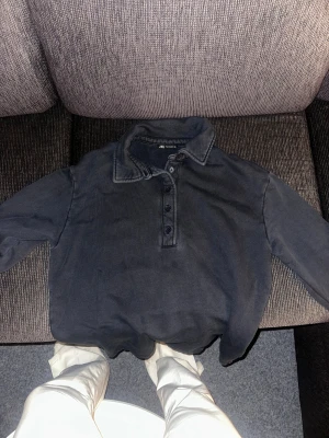 Mörkgrå pikétröja från Zara - Säljer min killes mörkgrå pikétröja från Zara i storlek L. Tröjan har klassisk krage, tre knappar framtill och är långärmad. Mycket bra skick!!