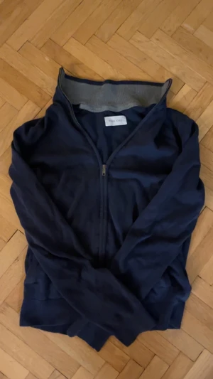 Marinblå kofta från Pier One - Snygg marinblå kofta från Pier One med hel dragkedja framtill och ribbad grå krage. Perfekt för dig som gillar stilrena och enkla plagg. Koftan har långärmad design och är gjord i mjuk bomull som känns skön mot huden. Står att den är s men sitter som xs då den krympt, tveka inte att höras av vid intresse 😊