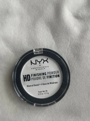Nyx Professionel Makeup HD Finishing Powder Translucent  - Oanvänd lätt genomskinlig finishing puder som hjälper till att dölja synligheten av fina linjer och porer. Den silkeslena pressade puder ger en fräsch matt finish.