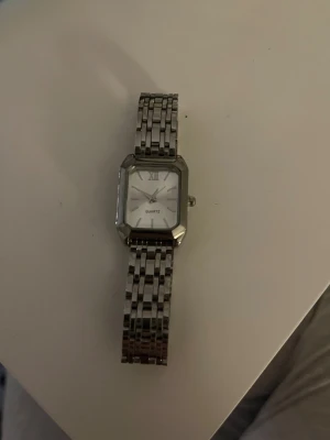 Klassisk silverfärgad fyrkantig klocka - Helt ny oanvänd silvrig klocka. Säljer för den var tyvärr för stor. Väldigt fin och väldigt bra skick, pris kan diskuteras. Köpt för 900kr