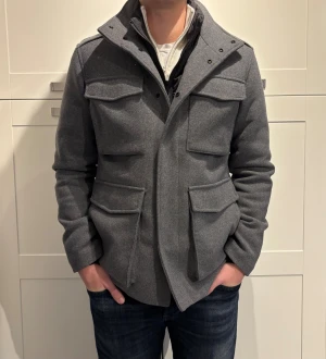 Grå jacka från Jack & Jones Premium med fickor - Grå jacka från Jack & Jones Premium. Den är varm och har en avtagbar dunväst under ullen. Köptes för 1399:-. Killen på bilden är 183