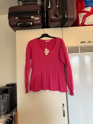 Odd Molly rosa Valerie blus - Odd Molly Valerie blus i färgen Pink Fudge. Blusen har långärmade puffärmar, smock upptill och en volang nedtill. Materialet är mjuk bomull och modellen har en rundad halsringning. Perfekt för dig som gillar färg och sköna detaljer. Från märket Odd Molly. Storlek 3 som enligt deras storleksguide motsvarar en L. Helt ny med tags/ prislapp fortfarande kvar. 