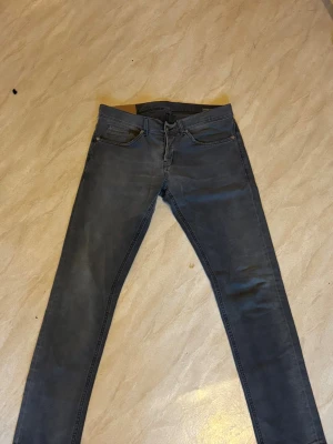 Grå slim jeans från dondup george - Snygga grå jeans från dondup george med fem fickor och diskreta detaljer. Jeansen har en slim passform och klassisk design med dragkedja och knapp. Perfekta för dig som gillar en stilren look och vill ha ett par bekväma jeans till vardags.