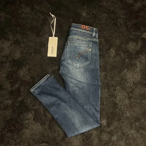 Dondup George  - Snygga Dondup jeans i mörkblå tvätt med klassiska fem fickor. Slim fit-modell med raka ben och låg midja. Perfekta för dig som gillar stilrena och bekväma jeans med coola detaljer.