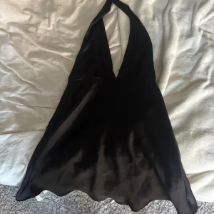 Svart festklänning från Zara - Säljer en svart omlottklänning från Zara med halterneck och djup v-ringning. Klänningen är kort och går att knyta som önskat i nacken. Hittar ej på hemsidan. Säljes på grund av dålig användning, perfekt till fest!!💞 Skriv för fler bilder eller frågor! 
