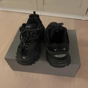 Svarta sneakers från Balenciaga - Säljer ett par svarta Balenciaga sneakers i storlek 44. De har en chunky design med snörning och är perfekta för en trendig look. Skorna är i nyskick och har en cool, modern stil.