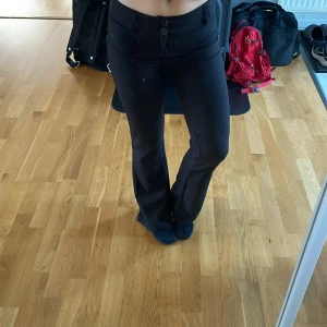 Svarta bootcut byxor Gina Tricot S - Snygga svarta bootcut byxor från Gina Tricot i storlek S. Byxorna har låg midja, utsvängda ben och dubbla knappar framtill. Sköna och stretchiga i materialet, perfekta för en trendig look.