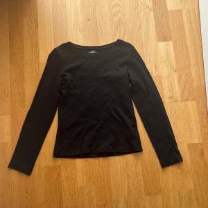 Svart långärmad topp från H&M L.O.G.G. - En basic svart långärmad topp från H&M:s L.O.G.G.-kollektion. Modellen har rund halsringning och är tillverkad i mjuk bomull, perfekt att styla med jeans eller kjol. Enkel och stilren design som funkar till det mesta.