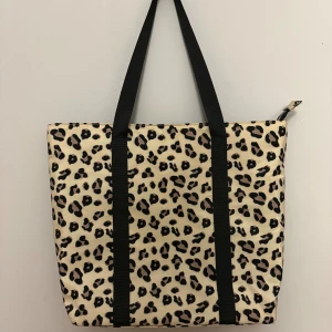 Leopardmönstrad väska med dragkedja - Väska i mycket fint skick med leopardmönster i beige och svart. Väskan har svarta handtag och stängs med dragkedja upptill. Insidan är svart med en innerficka som också har dragkedja. 💕