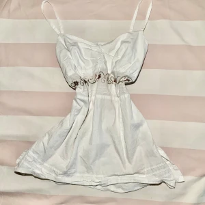 Vit topp från Bialcon! - Supersöt vit topp från Bialcon med tunna axelband och broderade blommor i midjan.Toppen har en feminin passform och är gjord i bomull, perfekt för varma dagar. Broderiet har inslag av rött och grönt som ger en unik touch.Priset kan sänkas!💕