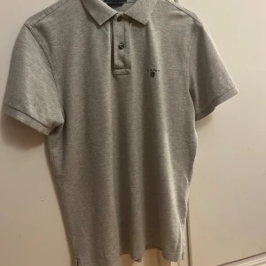 Grå pikétröja från Gant, Regular Fit - Klassisk ljusgrå pikétröja från Gant i Regular fit. Storlek S/36. Mycket bra skick