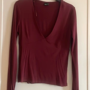 Vinröd tröja från Gina  - Säljer en vinröd tröja från Gina, med djup urringning superfin nu till hösten och den har även hål för tummarna längst fram