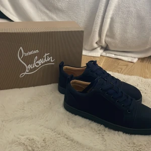 Christian Louboutin marinblå sneakers - Snygga marinblå sneakers från Christian Louboutin med klassisk röd sula och diskret logga. Skorna har snörning, rund tå och är tillverkade i mocka med beige innersula. Perfekta för dig som vill sticka ut med exklusiv stil. Pris kan diskuteras! Anledning till att jag säljer vart scammad och fick fel skor och har ej sickat de jag skulle ha❤️.